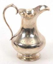 A Victorian silver jug of plain baluster form engraved with initials, having reeded rims and