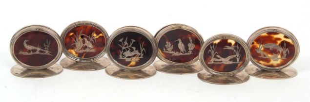 A group of six George V silver and tortoiseshell menu place card holders, the oval tortoiseshell