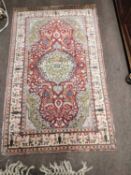 A small 20th Century Middle Eastern silk mix rug with a large central red medallion, worn condition,
