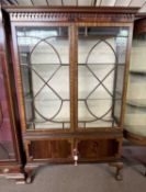 An Edwardian mahogany display cabinet with two astragal glazed doors over two panelled doors, raised