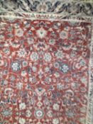 A 20th Century small Kashan type floor rug decorated with a central panel of flowers on a red