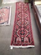A small Afghan runner carpet decorated with red lozenges on a black background, 213 x 59cm
