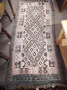 An antique Kilim carpet decorated with a geometric design, 190 x 82cm (faded throughout)