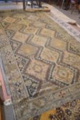 A large 19th Century pale ground Middle Eastern rug decorated with a central panel of stylised