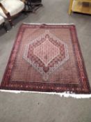 A 20th Century Middle Eastern wool floor rug with large central medallion on a principally red and
