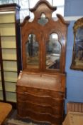 A reproduction walnut Italian bureau bookcase with large arched pediment with central mirror over