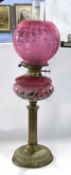 A late 19th Century oil lamp with pink shade and reservoir painted with flowers abvove a brass stem