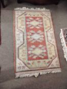 A small 20th Century Turkish wool floor rug decoorated with a central red medallion with stylised