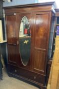 An Edwardian mahogany wardrobe with moulded cornice over a body with single door with bevelled