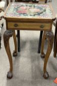 An early 20th Century lamp table, the top inset with a tapestry panel under glass, the body with a