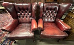 A pair of button back red leather wing back chairs raised on cabriole legs