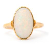 An opal ring, with single oval opal cabochon, approx. 14mm long, collet mounted with plain band
