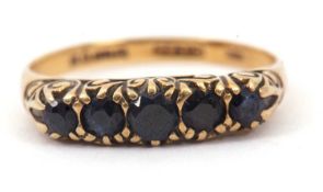 A 9ct five stone sapphire ring, the slightly graduated round sapphires with scrolled gallery and