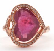 A rose gold, ruby and diamond ring, the heart shape treated ruby with a halo surround of small round