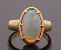 An opal ring, the oval opal cabochon, approx. 14mm long, in claw and collet mount with tapered