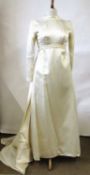 A 1960's wedding dress, in cream satin with hig neck and fitted bodice, long sleeves and lace