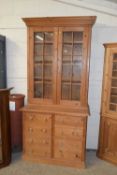 A modern pine dresser with moulded cornice over two panelled doors, the base section with a door