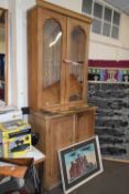 A pine dresser with glazed doors and cupboards below