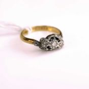 An 18ct gold and platinum diamond three stone ring, the illusion set diamond highlights in crossover