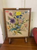 A mid-20th century oak framed fire screen with floral needlework under glass