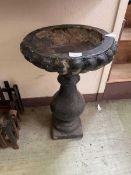 A weathered black painted composite stone garden birdbath