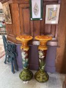 A pair of 20th century green ground jardiniere stands with hand painted floral decoration (one A/F)
