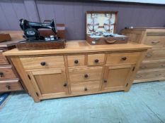 A modern oak sideboard with six drawers and two cupboard doors