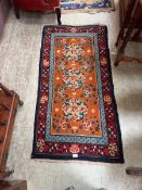 An eastern style orange ground hand woven rug with floral decoration