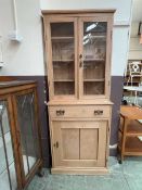 A stripped pine full height bookcase, the top with glazed doors over the base with single drawer