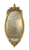 A 19th century wall mirror, the oval plate within a giltwood and plaster frame surmounted by a