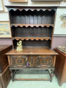 An oak dresser of two cupboards over stretchers with a plate rack above