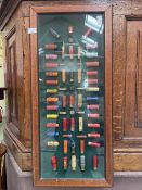 An oak wall mounted display case of spent shotgun shells