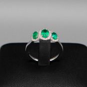 A PLATINUM EMERALD AND DIAMOND TRILOGY CLUSTER RING.