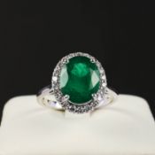 AN 18CT WHITE GOLD EMERALD AND DIAMOND CLUSTER RING.