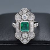 A PLATINUM EMERALD AND DIAMOND SET PANEL RING.