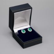 A PAIR OF 9CT WHITE GOLD EMERALD & DIAMOND CLUSTER STUD EARRINGS.