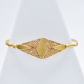 A YELLOW METAL CHILDS BANGLE.