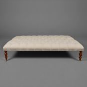 HEARTH STOOL WITH NEUTRAL LINEN BUTTONED UPHOLSTERY ON TURNED SUPPORTS.