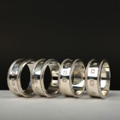 A SET OF FOUR ALGERNON ASPREY SILVER NAPKIN RINGS.