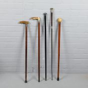 A COLLECTION OF FOUR WALKING STICKS AND A CARRIAGE WHIP. (5).