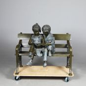 CONTEMPORARY SCHOOL STUDY OF BROTHER AND SISTER READING ON BENCH.