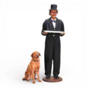 A life size figure of a butler, Carson, dressed in coat and tails, wearing a top hat, on a wooden