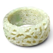 A Chinese carved celadon jade coloured stone bangle, of pierced scrolling lotus design, 75mm
