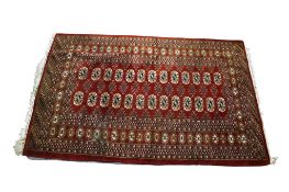 A small Bokhara style wool rug on a burgundy ground.