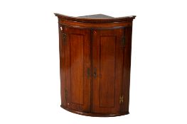 A George III oak and mahogany cross banded bow fronted wall hanging corner cupboard.
