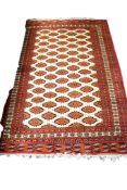 A large Turkamen style wool rug on a red ground.