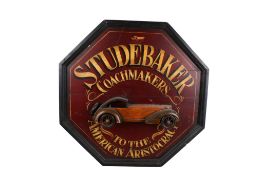 A painted wood 'Studebaker' reproduction sign. Octagonal, gold lettering on a Burgundy ground.
