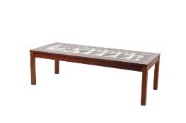 A mid-century coffee table with a decorative enamel inset top. Raised on square chamfered supports.