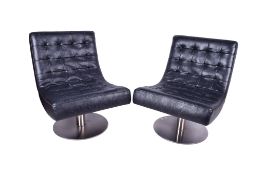 A pair of black New Yorker lounge chairs. Raised on a pedestal with heavy circular metal base.