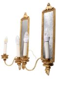 A pair of contemporary antique style two light wall sconces with mirror backs and gilt finish.
